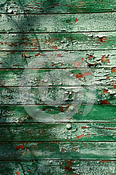 Old dark green wall from wooden planks with paint traces