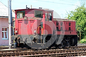 Old dark red electric locomotive parked on railway tracks waiting for departure from railway station