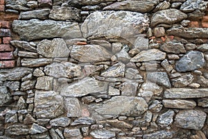Old dark stone wall built of different stones, texture, pattern irregular background