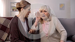 Old deaf woman listening senior friend, hearing disease, old age health care