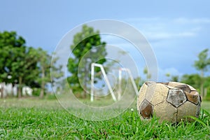 Old deflated soccer ball, old deflated football on the green grass