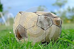 Old deflated soccer ball, old deflated football on the green grass