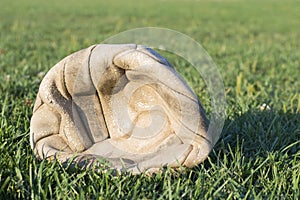 Old deflated soccer ball on the soccer field grass