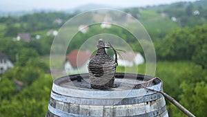 Old demijohn wicker wrapped glass bottle on a barrel