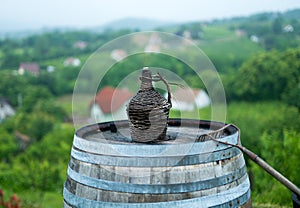 Old demijohn wicker wrapped glass bottle on a barrel