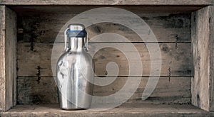 old dented metal bottle on wooden background photo