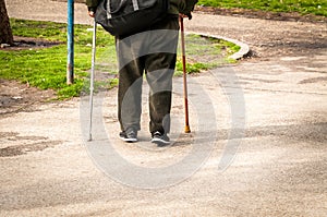 Old depressed man walk alone down the street with walking stick or cane feeling lonely and lost view from back
