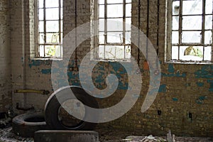 An old derelict building with broken windows, peeling paint and three used tyres.