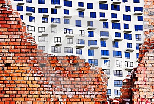 Old destroyed brick wall of the building and a new house under c