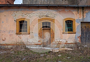 Old, destroyed building with door and two windows.