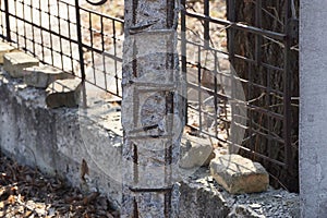 Old destroyed concrete pillar with rusty iron fittings on the street