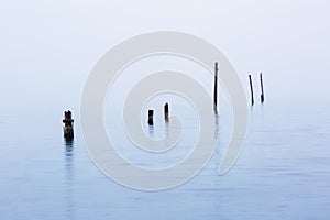 Old destroyed piles from a bridge into the sea in bad rainy weather
