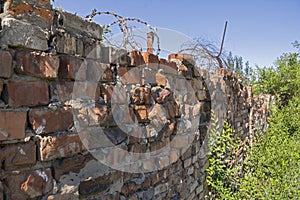 Old destroyed red brick wall with barbed wire