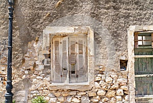 Old deteriorating stone wall with closed wooden shutters