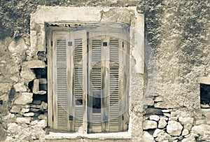 Old deteriorating stone wall with closed wooden shutters