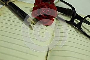 Old diary with rose and spectacle placed on it