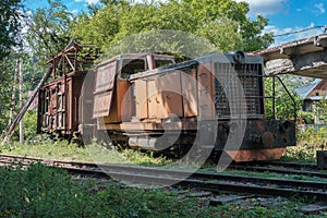 Old diesel locomotive with broken wooden cargo wagon on railway