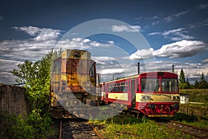 Old diesel locomotive in train cemetery in the summer with green grass and trees in the background and great cloudy sky