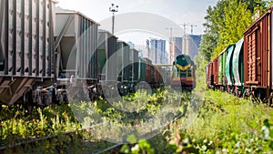 Old diesel train riding on railroad between rows of cargo wagons and cars