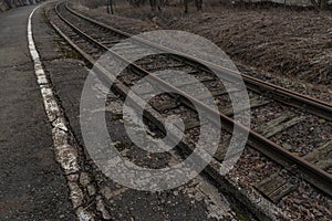 Old, dilapidated and abandoned railway station with rusty railway tracks and wooden railway sleepers