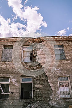 An old dilapidated brick building with a hole in the wall. The concept of postapocalyptic, abandonment