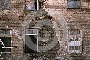 An old dilapidated brick building with a hole in the wall. The concept of postapocalyptic, abandonment