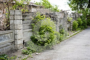 Old dilapidated cinder block fence and wooden boards