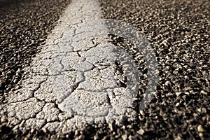 Old dilapidated, cracked road marking on an asphalt road