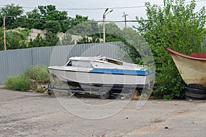 An old dilapidated fishing boat on a trailer in front of a gray
