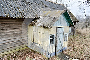 The old dilapidated porch, the entrance to the wooden village house and the wall of dilapidated logs of an abandoned village house