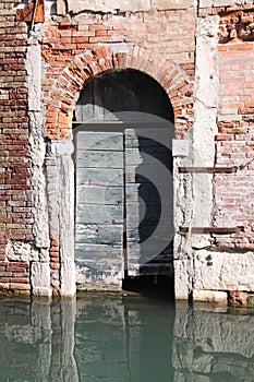 old dilapidated wooden door in a brick facade inundated by a Venice canal