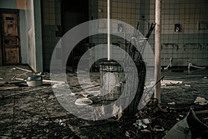 An old dirty bucket with dead branches stands in an abandoned building. Oppressive atmosphere.