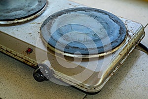 An old, dirty electric stove covered in grease on the table