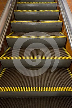 Old dirty escalator with yellow warning stripes in the subway