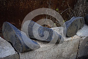Old dirty galoshes on bricks in rural yard