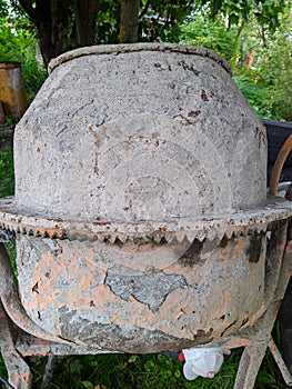 old dirty and gray cement mixer in the yard