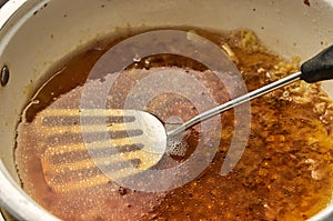 Old dirty greasy pan with a spatula closeup. Droplets of oil mixed with water