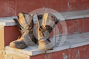 Old and dirty military boots on the steps of the porch. Close-up