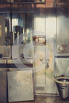 Old dirty public toilet with metallic interior photo