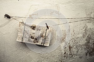 Old dirty rag hanging on a wire. Antique wall background