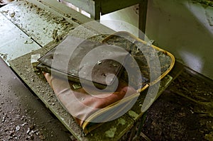 Old dirty school bag and folder for papers on desk in abandoned elementary school in village of Dronki in exclusion zone of