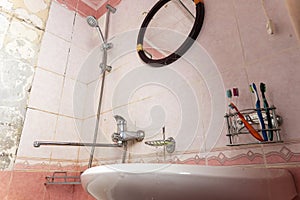 an old dirty shabby bathroom with fallen tiles. an old ruined bathroom