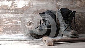 Old dirty shoes boots boots and hammer on a wooden background