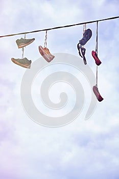 Old dirty shoes hanging on wire.