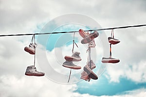 Old dirty shoes hanging on wire.