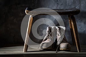 Old dirty shoes under a wooden bench against a dark wall