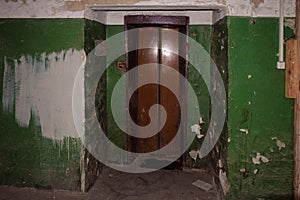 Old dirty walls and entry doors of elevator in an abandoned house