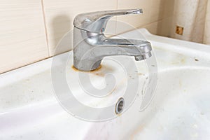 Old dirty washbasin with rust stains, limescale and soap stains in the bathroom with a faucet, water tap