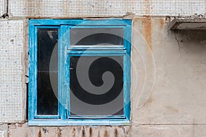 Old dirty window in blue wooden frame in abandoned house