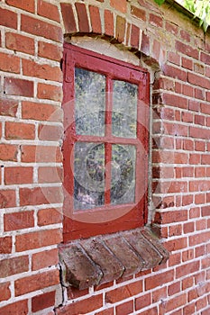 Old dirty window in a red brick house or home. Decaying casement with redwood frame on a historic building with clumpy photo
